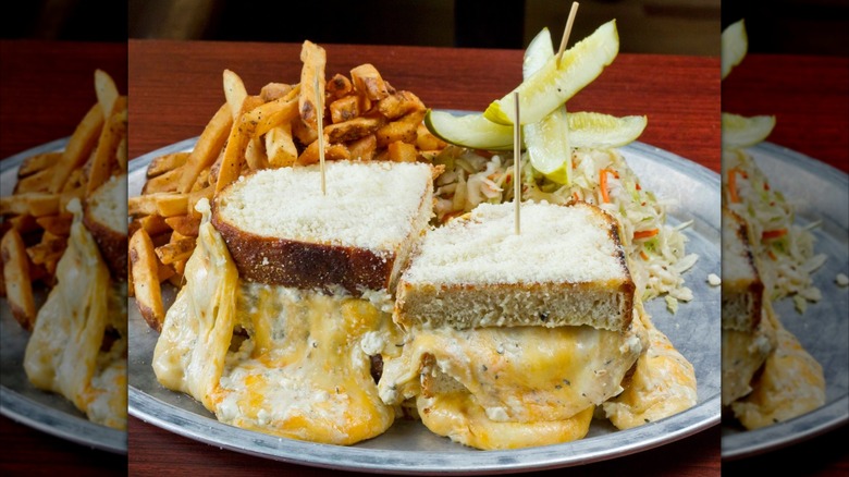 Mirrored image of giant grilled cheese with fries, coleslaw, and pickles