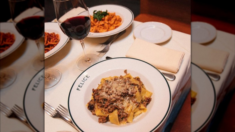 Italian pasta dishes on a table with a glass of red wine
