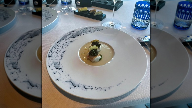 langoustine and caviar dish on plate on table, mirrored image
