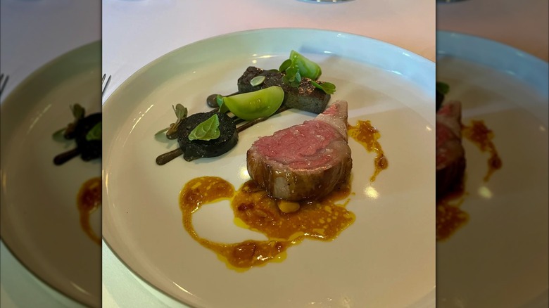 steak dish on plate on table at The French Laundry, mirrored image