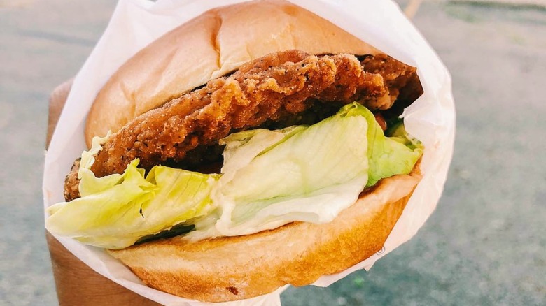 Hand holding Hardee's chicken fillet in wrapper