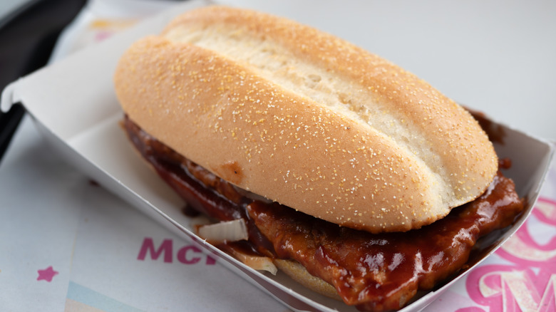 McDonald's McRib sandwich in paper container on top of McDonald's wrapper