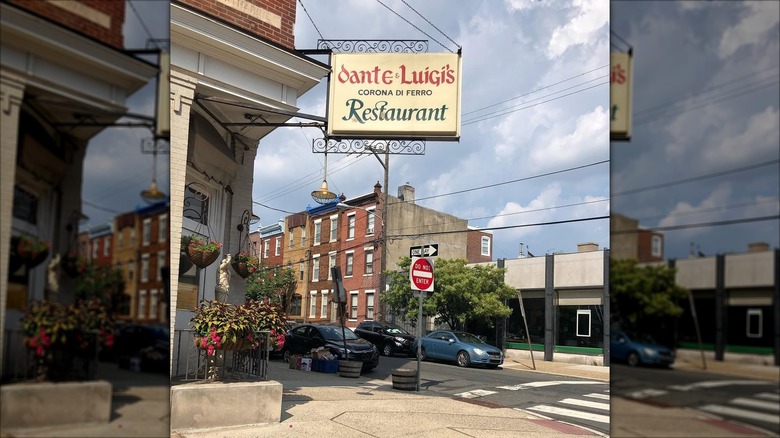 Mirrored image of Dante & Luigi's sign hanging outside restaurant on street