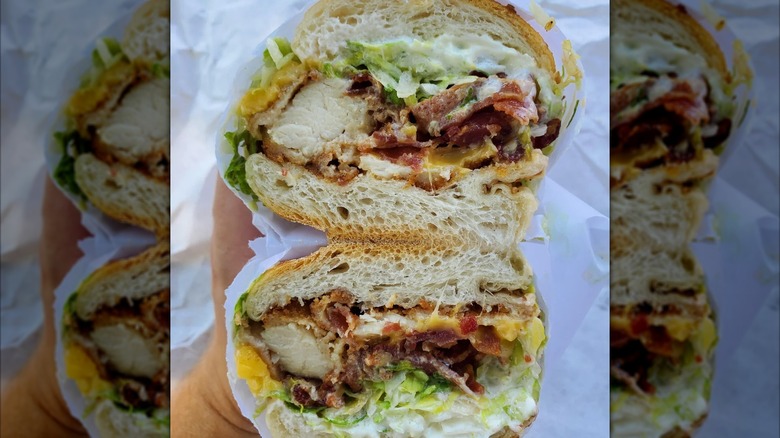 Mirrored image of hand holding stacked sandwich from DeFonte's