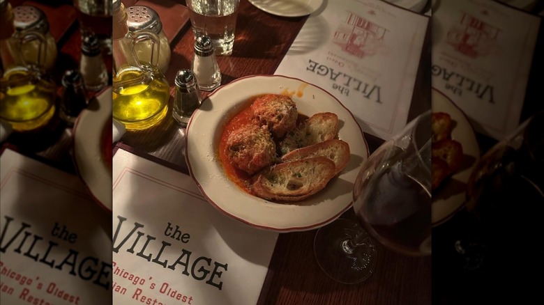 Dimly lit table with meatballs and garlic bread and The Village menus