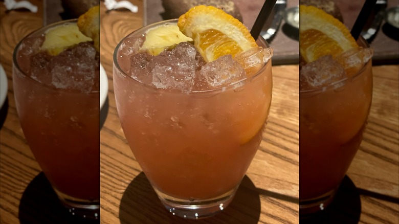 Outback Steakhouse's Castaway Cocktail with orange garnish on a table with bread tray in the background, with mirror borders