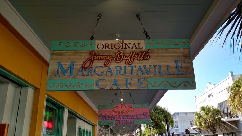 Jimmy Buffett's Margaritaville Cafe sign hanging from ceiling outside of cafe, beside the street to the right
