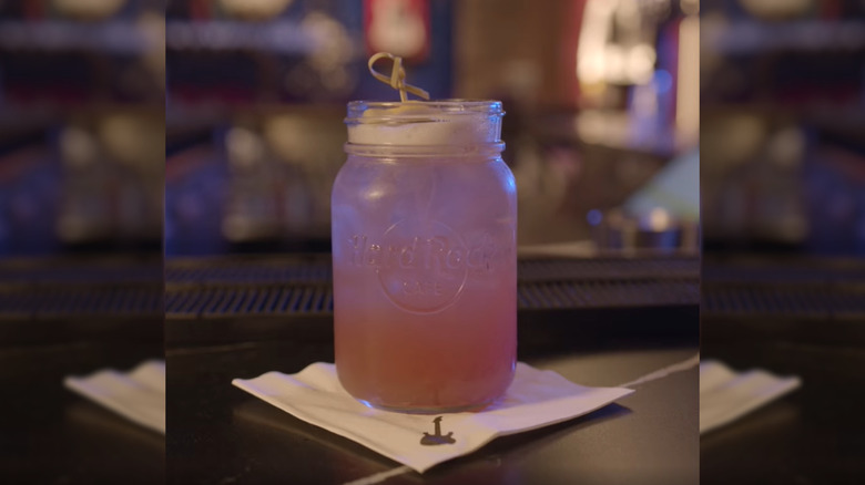 Hard Rock Cafe's Southern Rock cocktail in a mason jar glass on a bartop sitting on a napkin, with mirror borders