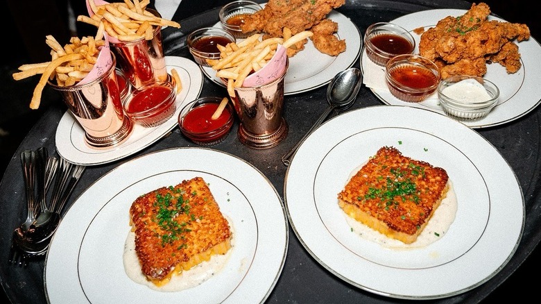 Plates of baked macaroni, fried chicken, and french fries at Delilah Miami