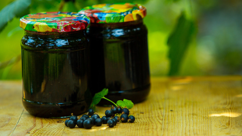 Two jars of currant jelly with black currants on the side