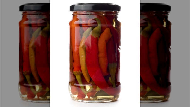 A mirrored image of a jar of pickled chilis