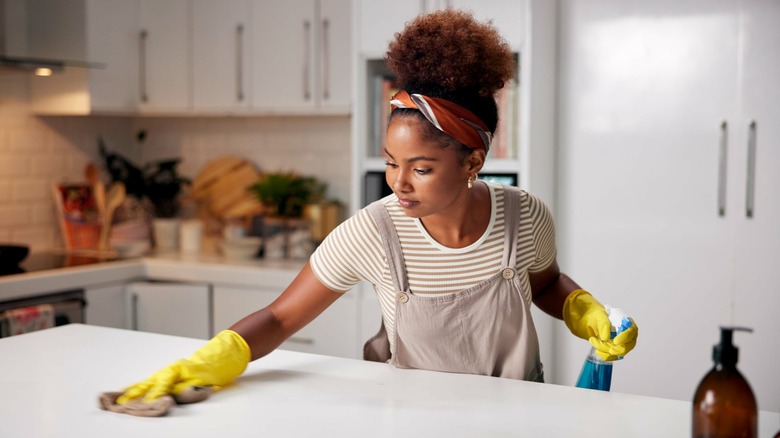 Person wiping counter top after spraying with cleaning product