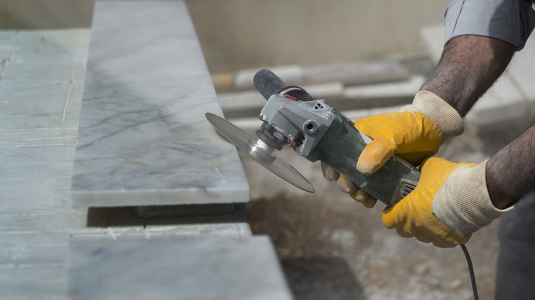 Someone holding an angle grinder on a marble slab
