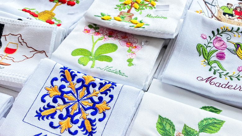 Several embroidered Madeira-themed kitchen towels laid out together