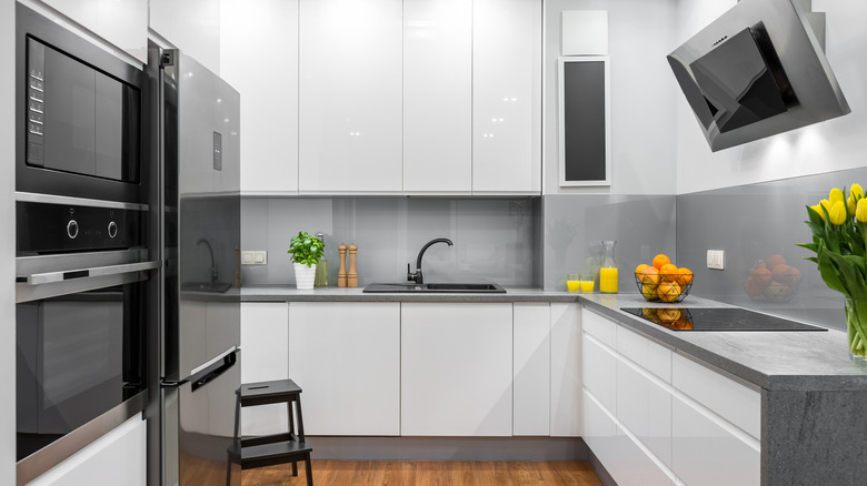 Well-lit kitchen with refrigerator, stove and sink placed in a triangular formation