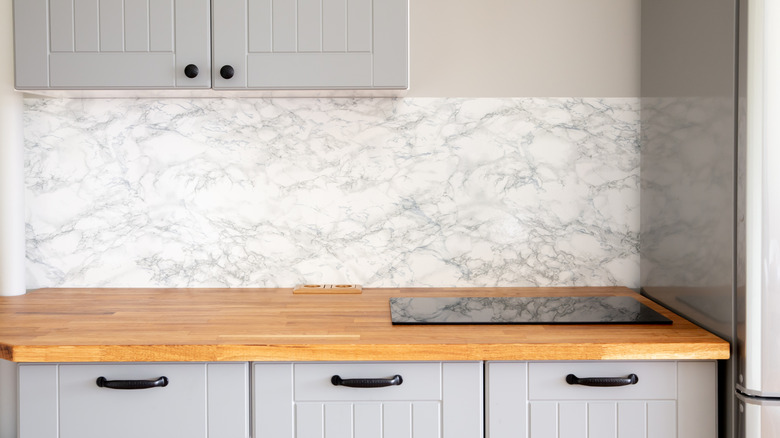 Butcher block countertop and gray cabinets in empty kitchen