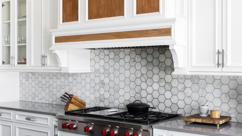 Detail shot of kitchen range hood over hexagonal tiled backsplash