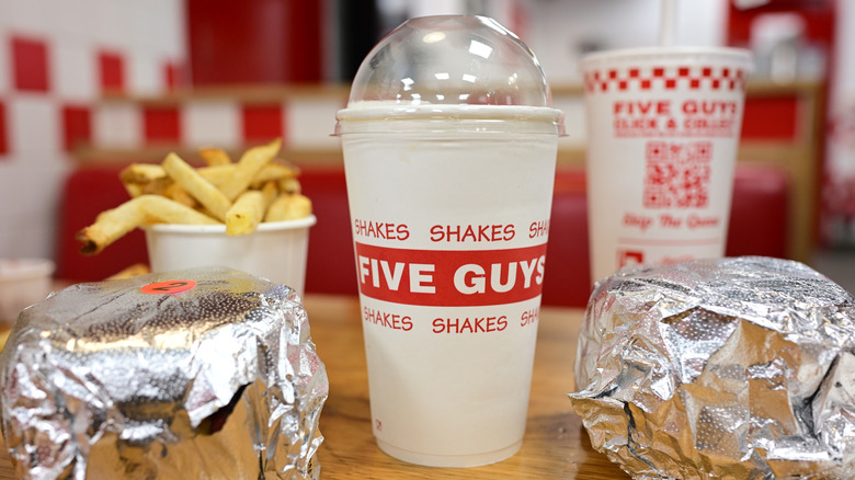Five Guys interior table with burgers, a shake, drink, and fries