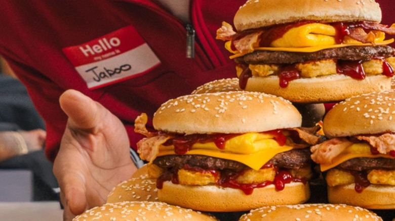 Tray of burgers with a Carl's Jr. employee blurred in the background