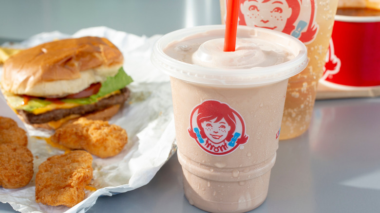 Wendy's Frosty and a drink, with a burger, nuggets, and chili on a table