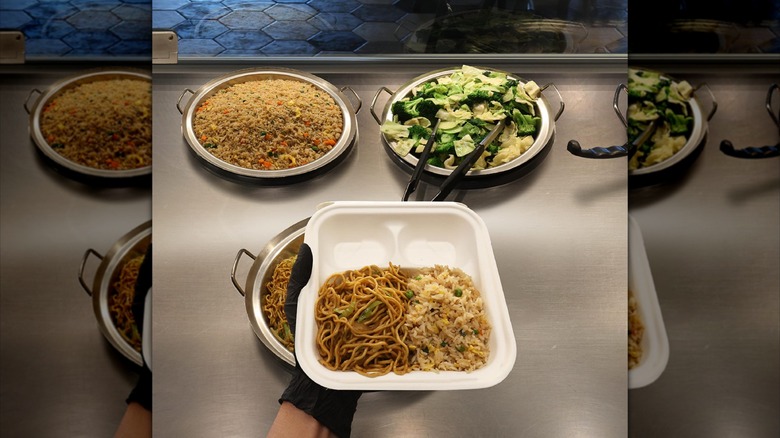 Server's hand holding Panda Express plate with fried rice and chow mein