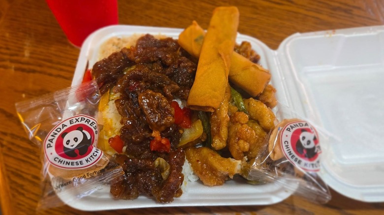 Panda Express order in styrofoam container with egg rolls and fortune cookies on top