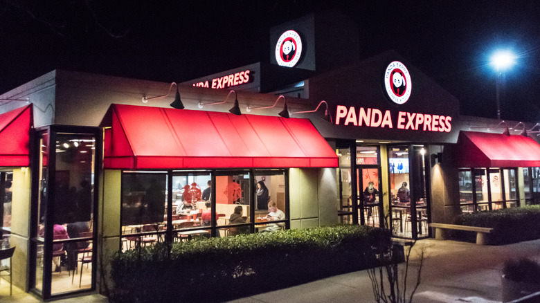 Outside an open Panda Express at night with people inside eating