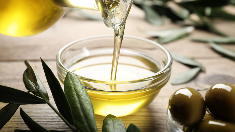 Pouring olive oil from jug into bowl