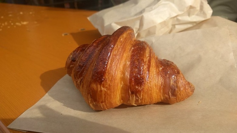 Butter croissant on pastry paper, glistening in sunlight