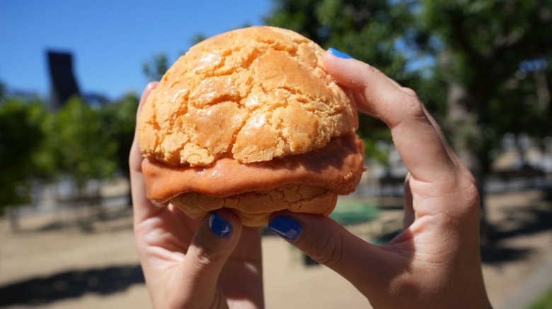 Hands holding a guava butter pineapple bun