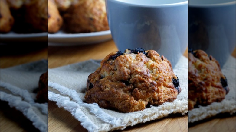 Blueberry pecan scone on cloth napkin in front of mug
