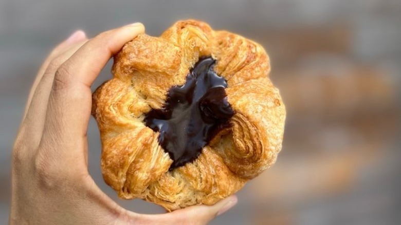 Hand holding kouign-amann filled with chocolate