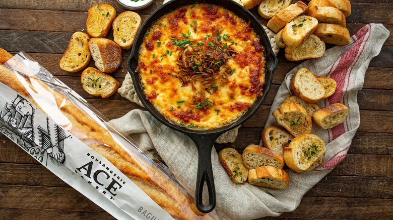 ACE Bakery baguette with French Onion Soup in a black skillet, surrounded by garlic bread slices