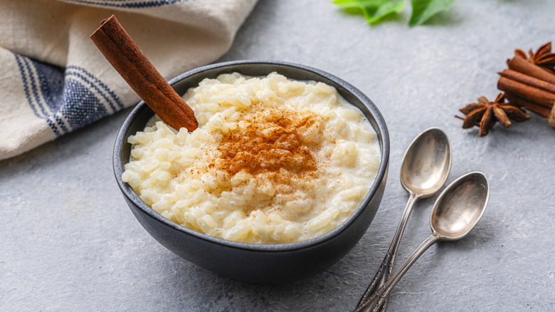 Bowl of rice pudding with cinnamon stick and ground cinnamon garnish
