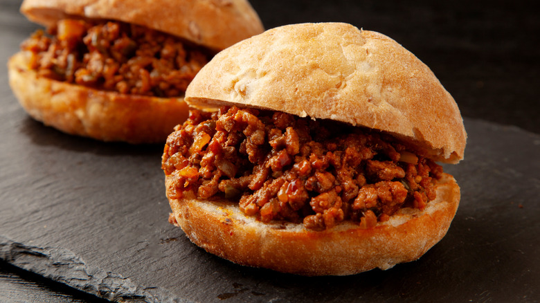 Two sloppy Joe sandwiches on a black slate