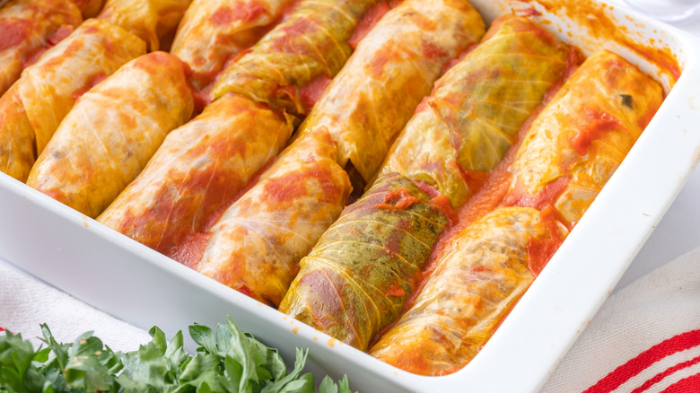 Stuffed cabbage rolls with tomato sauce in white baking dish