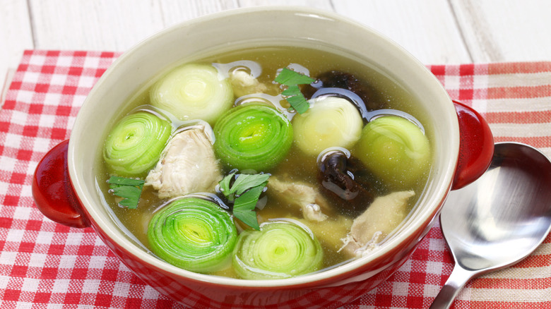 Red bowl of cock-a-leekie on red checkered table cloth