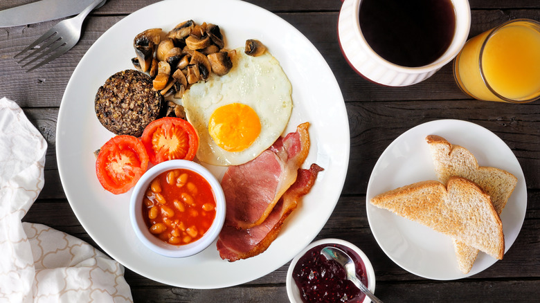 Full scottish breakfast on table with toast, juice, coffee, and pot of jam
