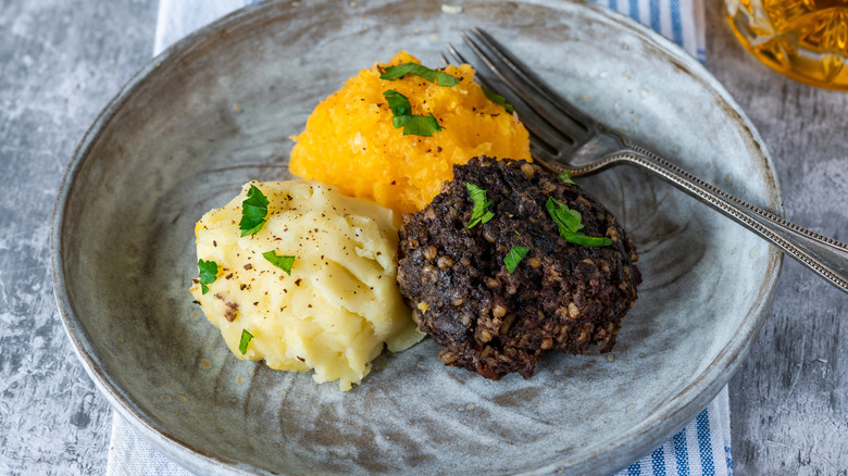Grey plate of haggis with turnips and potatoes with fork