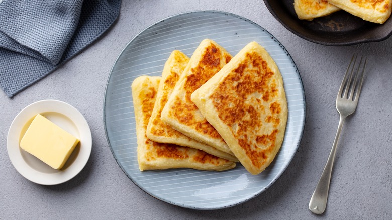 Plate of potato scones next to butter dish and fork