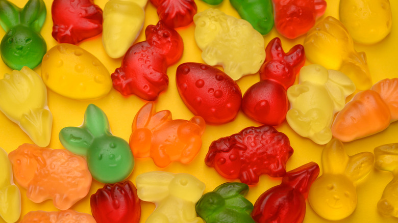 Colorful gummy candies arranged on yellow background