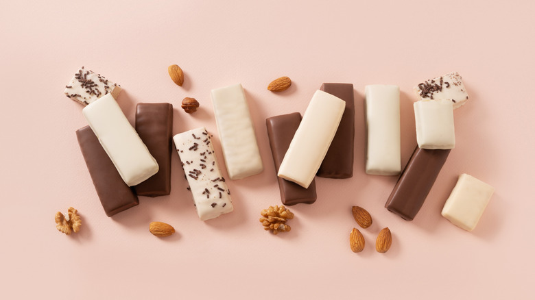 Protein bars arranged on pink background with nuts
