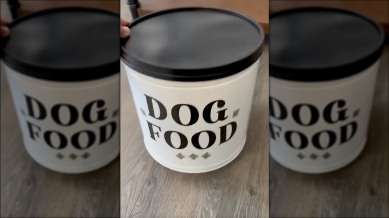 Hand taking lid off of popcorn tin turned into dog food container
