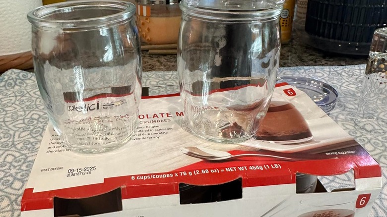 Empty glasses and lids on top of Delici Belgian chocolate mousse box