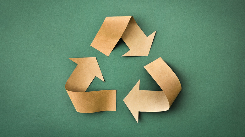 Recycling symbol made with paper arrows on green background