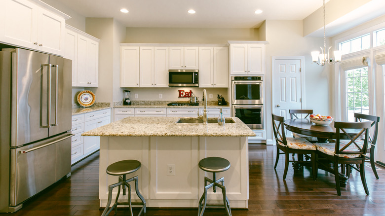 Contemporary open-plan kitchen with white cabinetry and bar stools