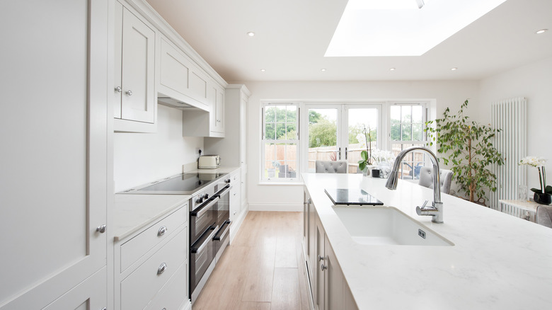 Interior of a dove grey kitchen with a white sink on the kitchen island