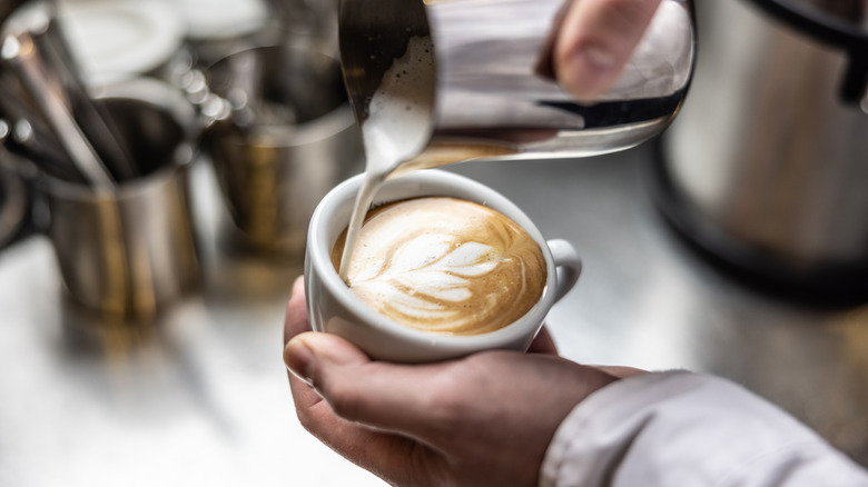 Close up of a barista making a cup of flat white by pouring milk