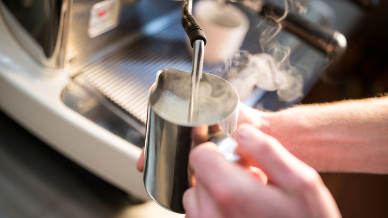 Close up of barista steaming milk using an espresso machine