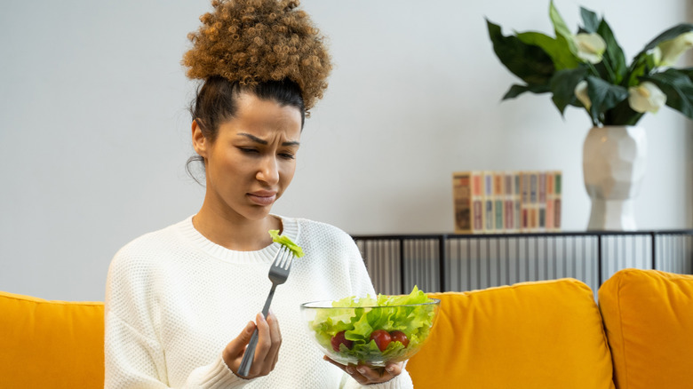 Woman looking at a salad with disgust